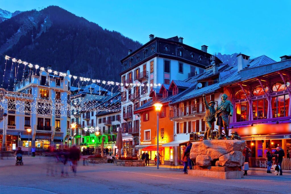 Place centrale de Chamonix en soirée, illuminations hivernales, statue de bronze et façades colorées, ambiance séminaire entreprise Chamonix