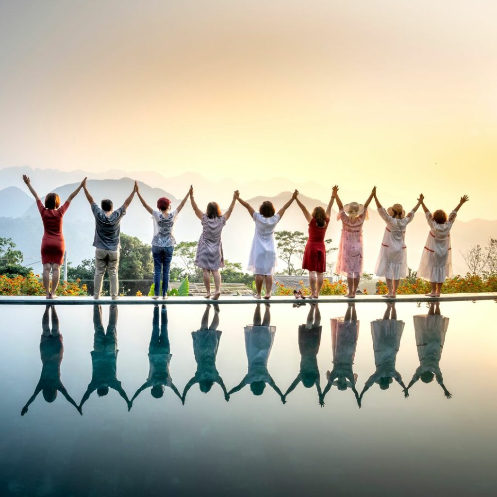 Groupe de participants levant les bras ensemble face à un paysage de montagne lors d’une learning expedition.
