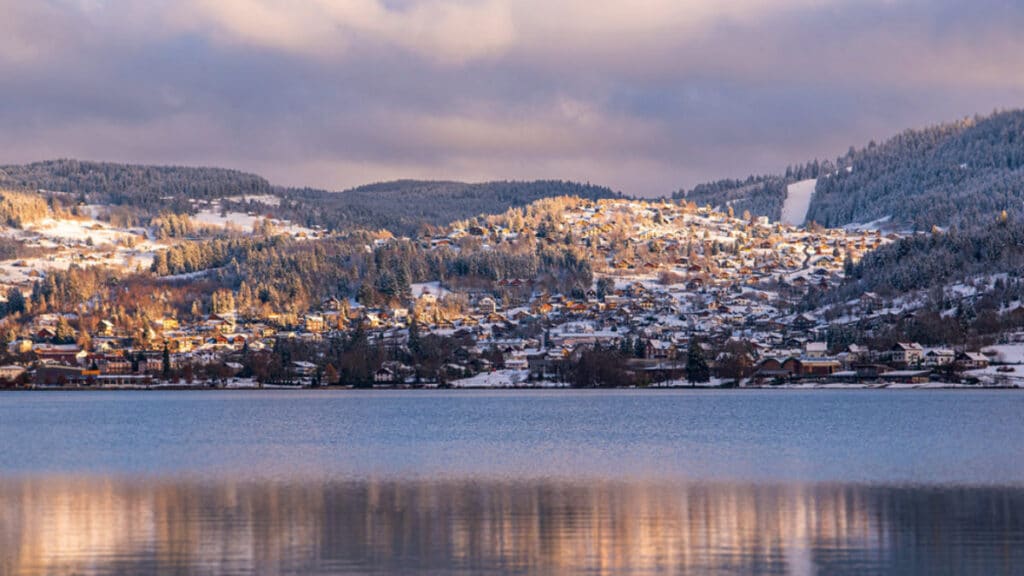 Vue hivernale sur Gérardmer enneigé depuis le lac, forêts et chalets sous la neige dans les Vosges – séminaire entreprise Gérardmer